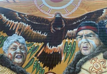 Painting of large eagle between Aunty Joyce and Uncle Boots dressed in traditional clothing.