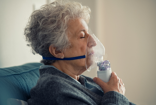 Mature woman treating asthma with inhaler at home