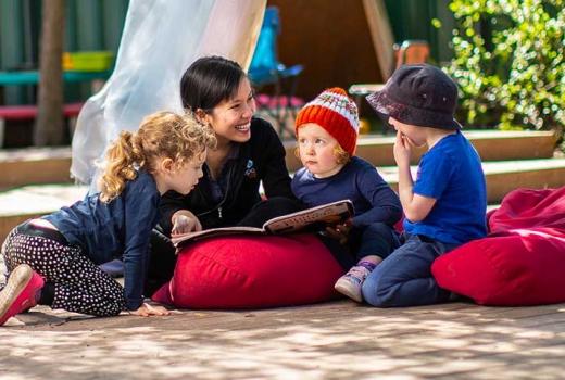 Female educator reading to 3 young children