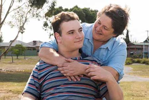Young man with disability being given a hug from carer