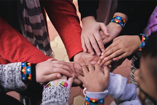 hands together wearing wrist bands with First Nations flags