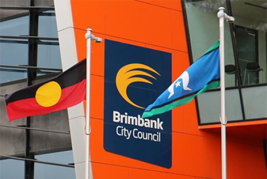Aboriginal and Torres Strait Islander flags flying into of Brimbank City Council logo on the side of Council offices