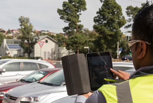 City compliance officer using ipad near parked cars