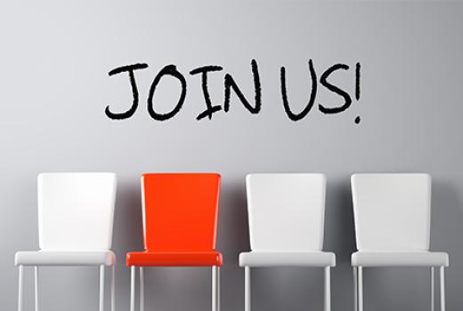 Four empty chairs (with the second one red while the others are white) against a wall with the words Join Us above the chairs