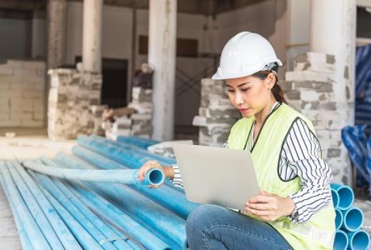 Asian woman construction engineer using notebook computer for checking the PVC pipe on construction site
