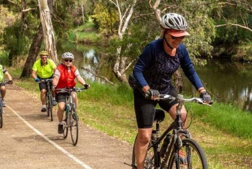 Cyclists riding on a shared user path that runs along a creek