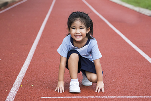 Young girl positioned to start a race on synthetic track