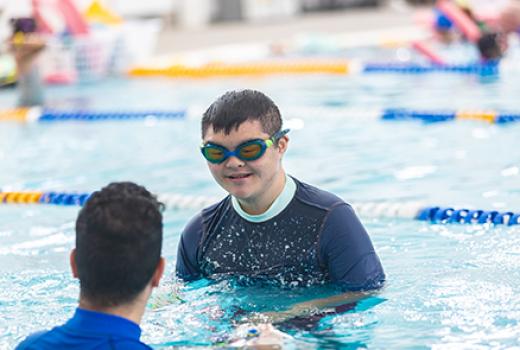 Young man with Down Syndrome in a pool with a swimming instructor